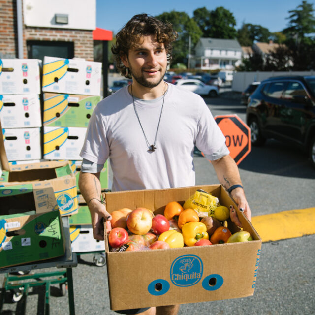 A man working for Boston area food recovery organization Lovin Spoonfuls carrying a box of donated fruit.