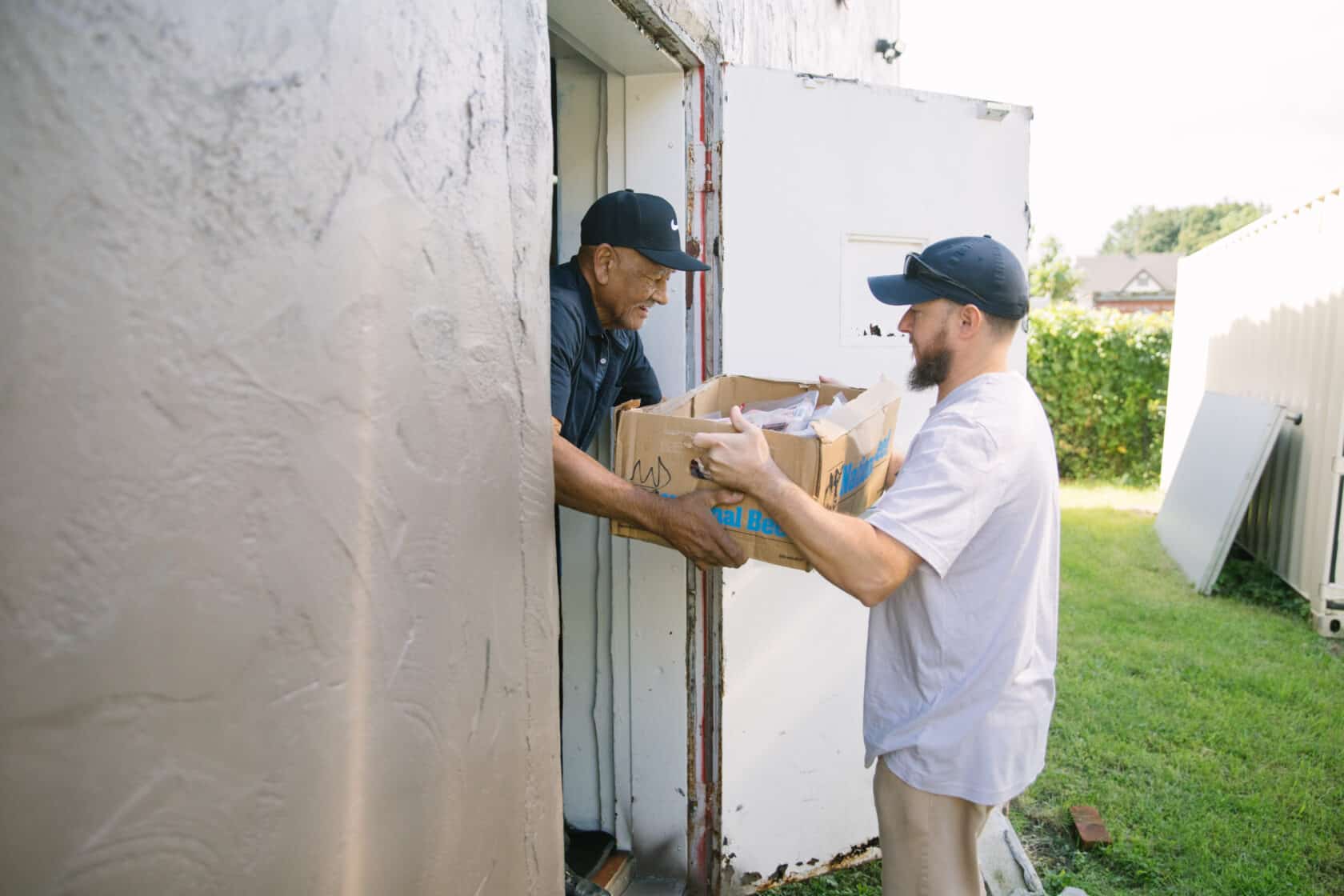 Two men delivering a box to a door.