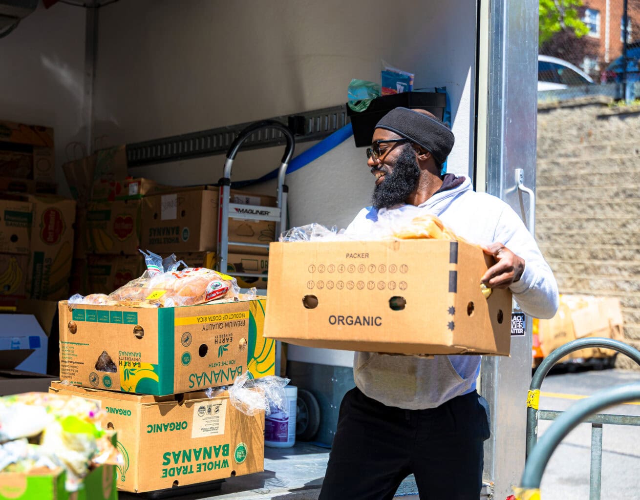 A Spoonfuls staff member moving a box of recovered food, demonstrating a career in food recovery.