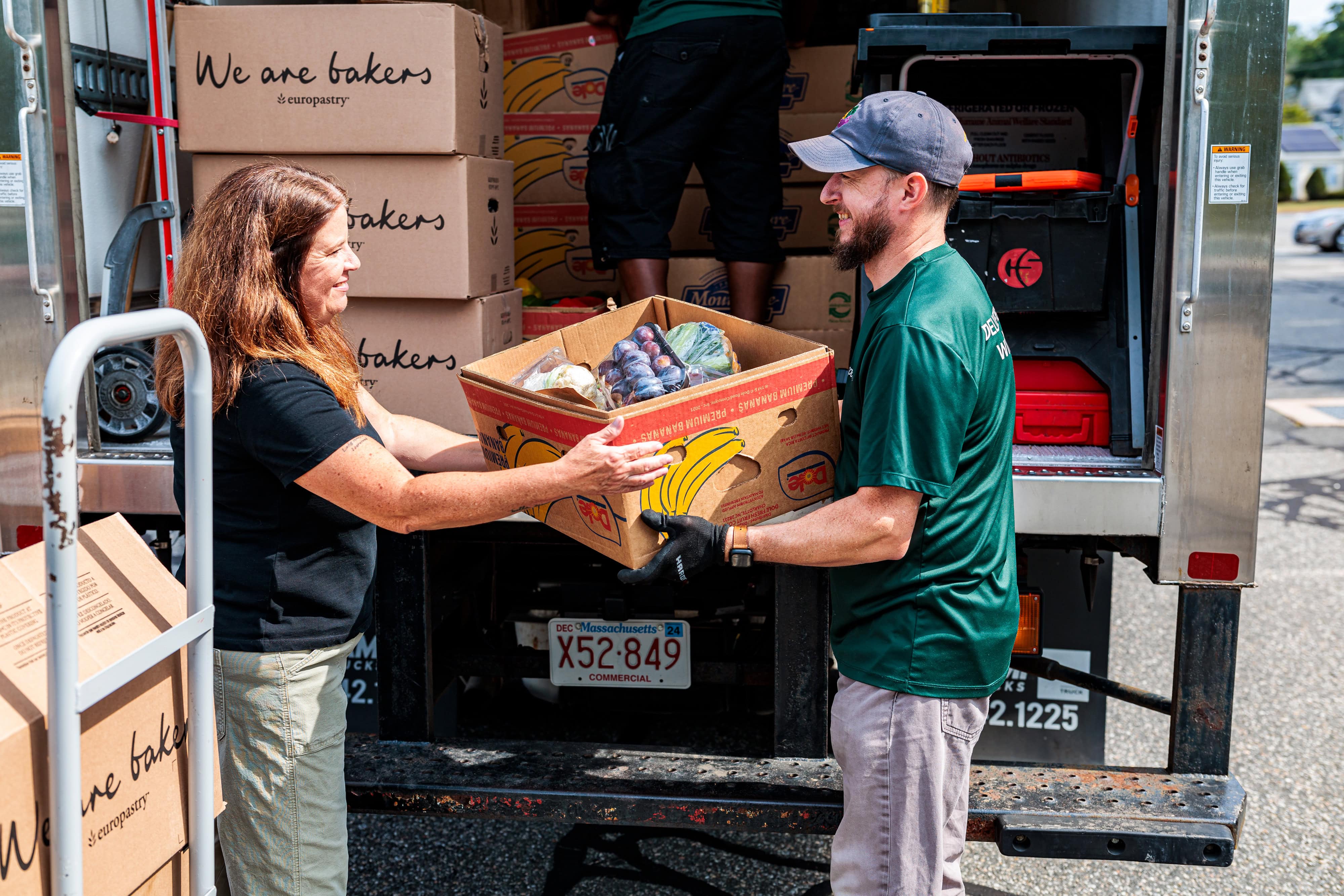 A Spoonfuls staff member hands off a box of produce to a community partners to help demonstrate our Core Values & Inclusion Tenets.