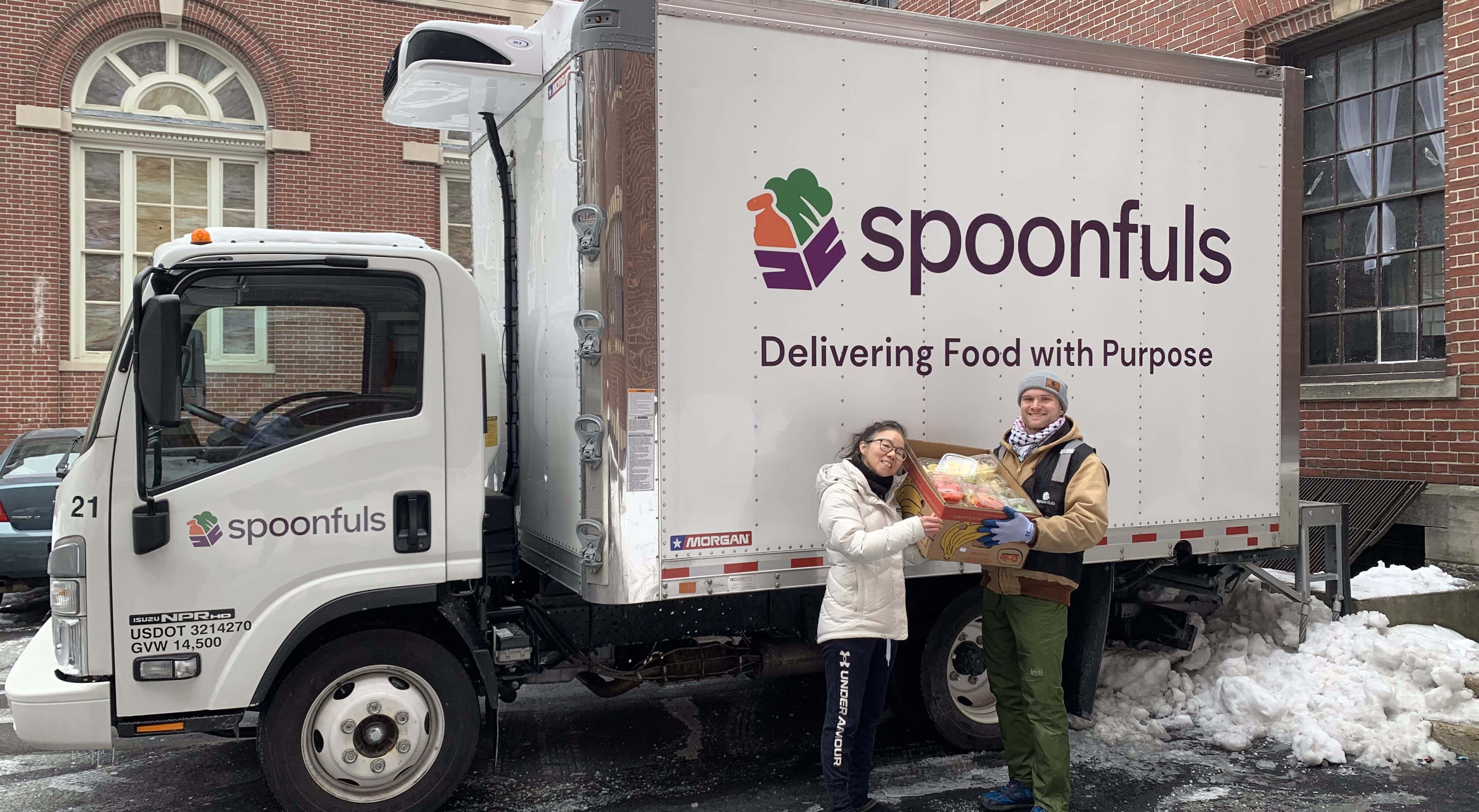 A Spoonfuls staff member and a community partner pose with a box of recovered food in front of a Spoonfuls truck to show how partnership is a part of our story. 